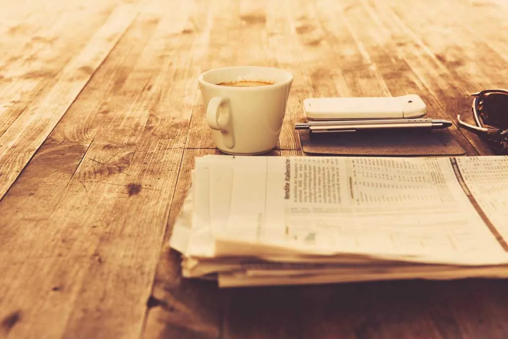 Newspapers and a cup of coffee on a wooden table