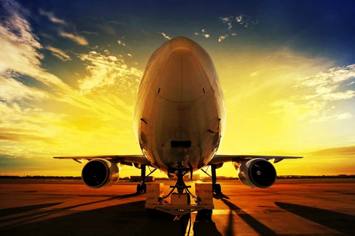 Passenger aircraft on the apron, seen from the front against a golden sunset